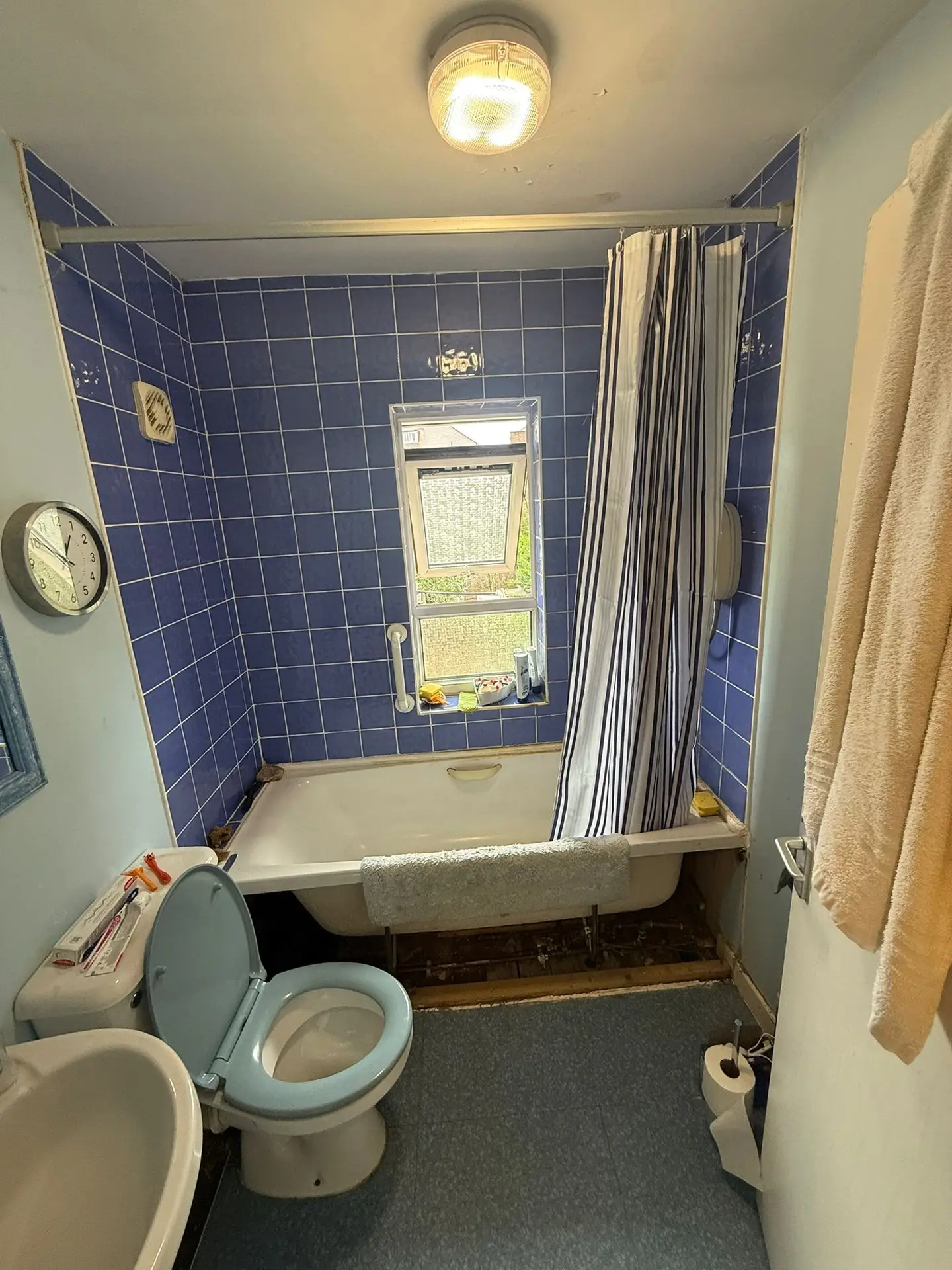 Blue-tiled bathroom with a bath, basin and toilet before the strip-out.